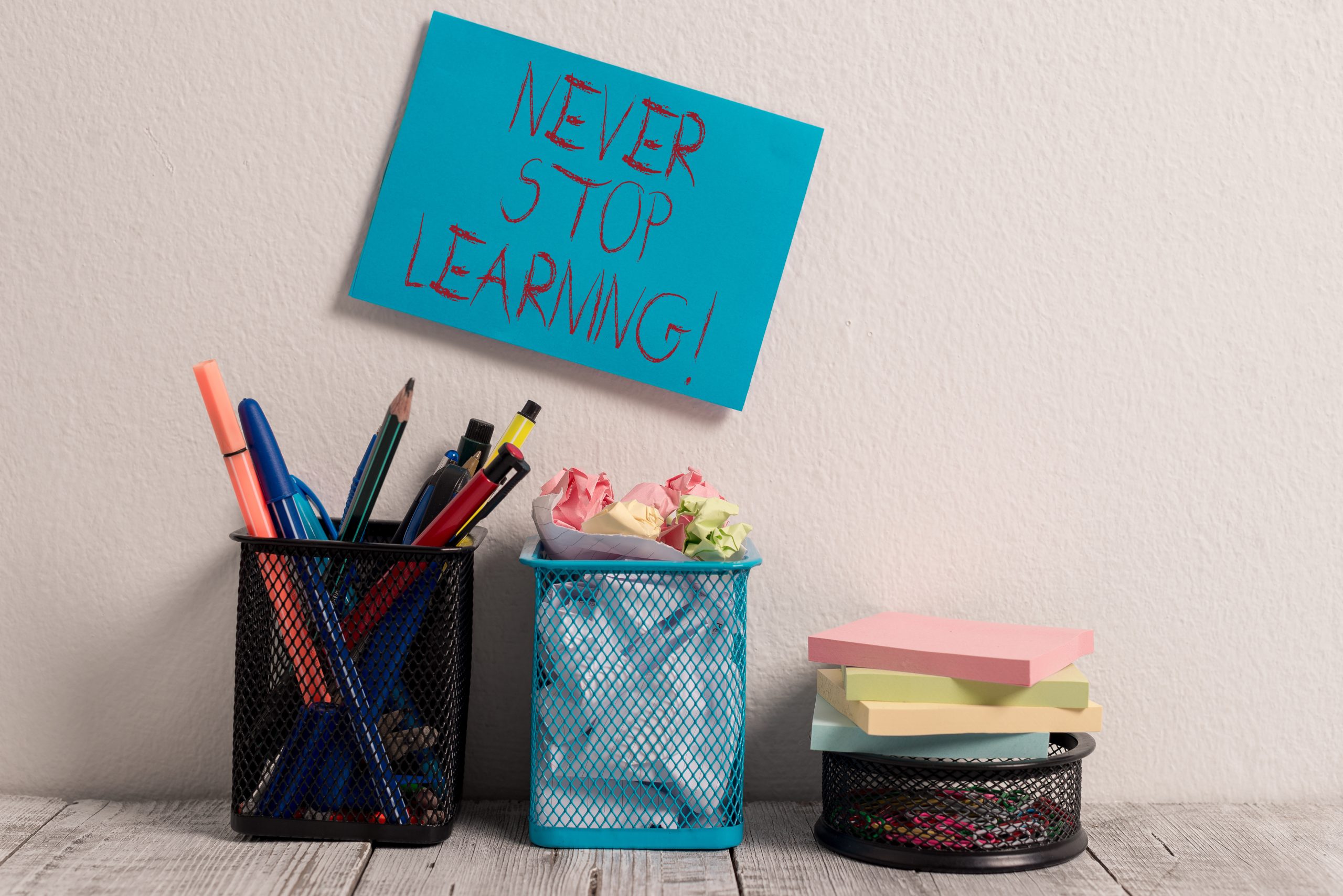 Conceptual hand writing showing Never Stop Learning. Business photo text keep on studying gaining new knowledge or materials Blue Sticky Card on Wall Two Pencil Pots Mesh Paperclip Notes.