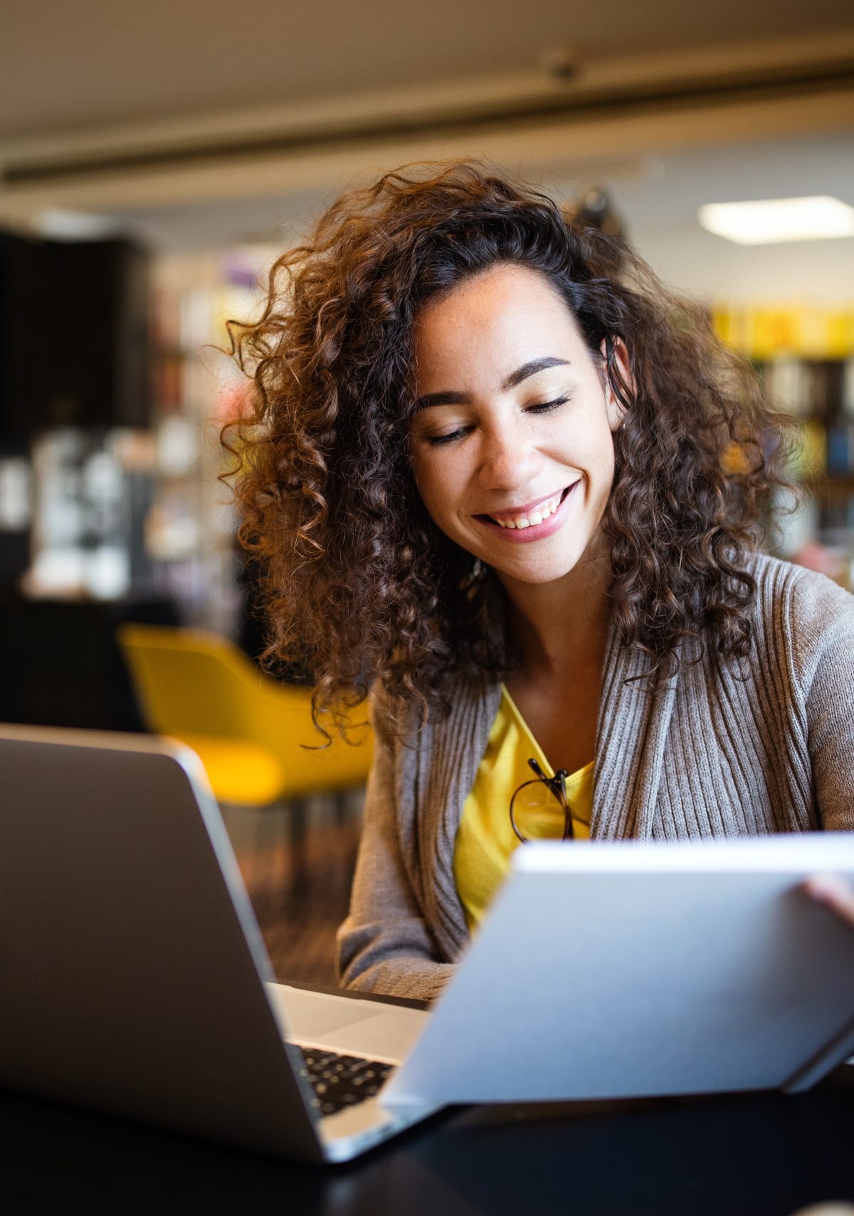 Young afro american woman sitting at table with books and laptop for finding information